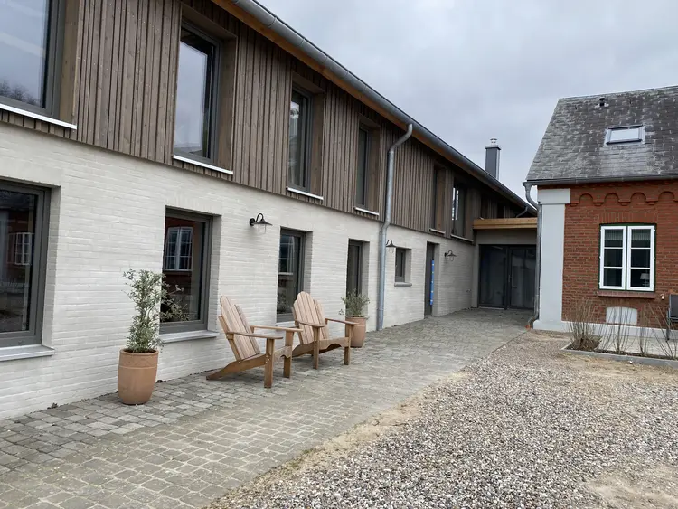 Außenansicht eines Hauses, welches zur Hälfte mit einer Holzfassade von der Malerei Norbert Bardtke verkleidet wurde. ist. 