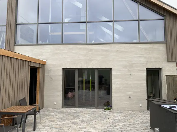 Nahaufnahme des Terrassenbereiches eines Hauses mit großen Fenstern und einer Zier-Holzfassade, die von Malerei Norbert Bardtke umgesetzt wurde. 