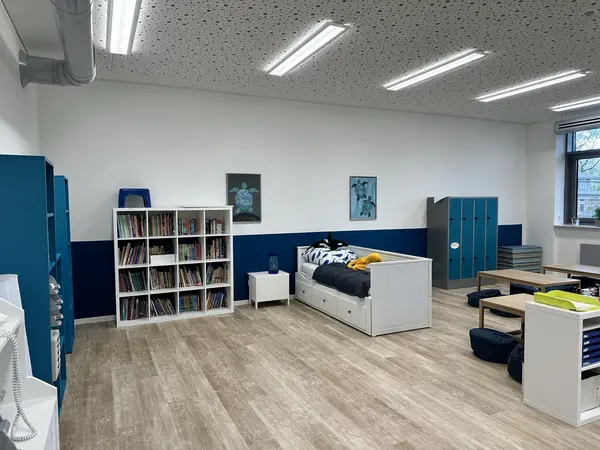 Es ist ein großes, eingerichtetes Zimmer zu sehen, dessen Wände in den Farben Weiß und Dunkelblau von der Malerei Norbert Bardtke gestrichen wurden.
